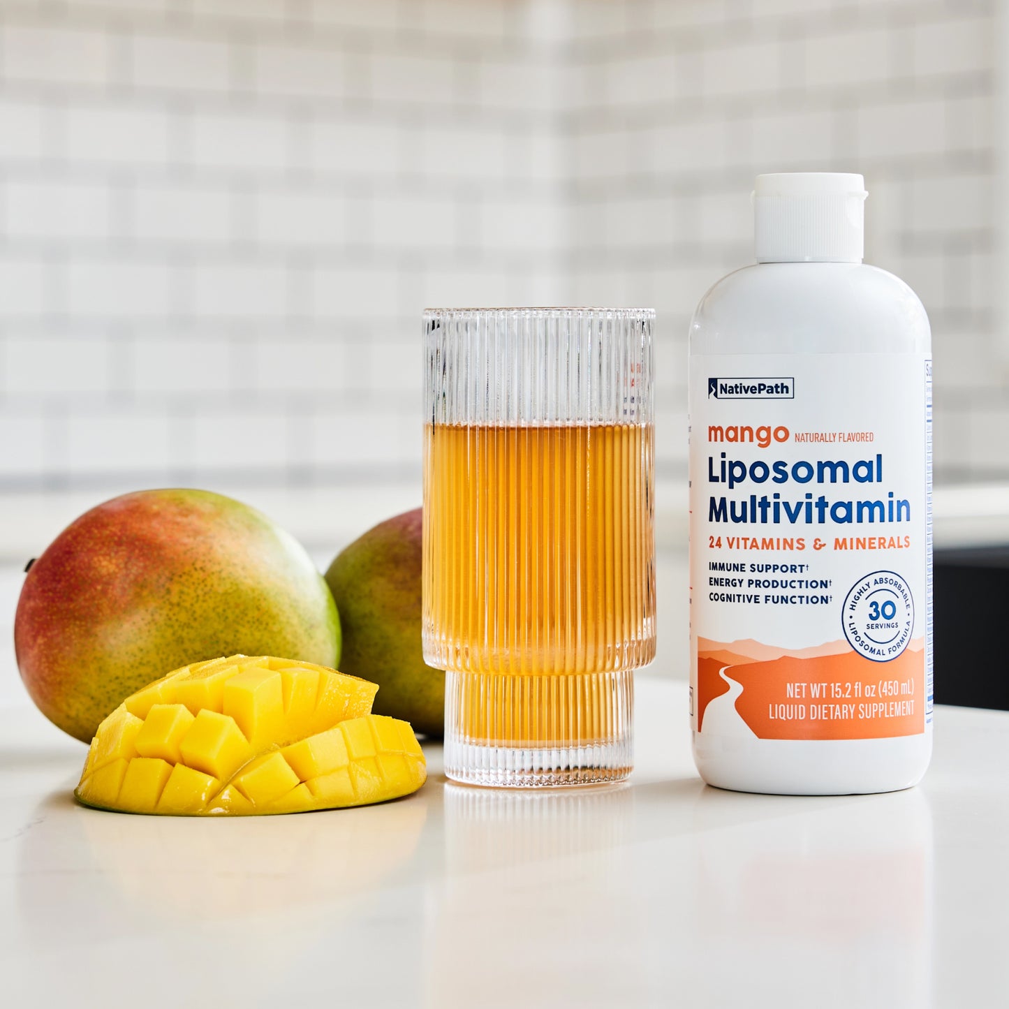 NativePath Liposomal Multivitamin mango flavor bottle lifestyle shot with fresh fruit
