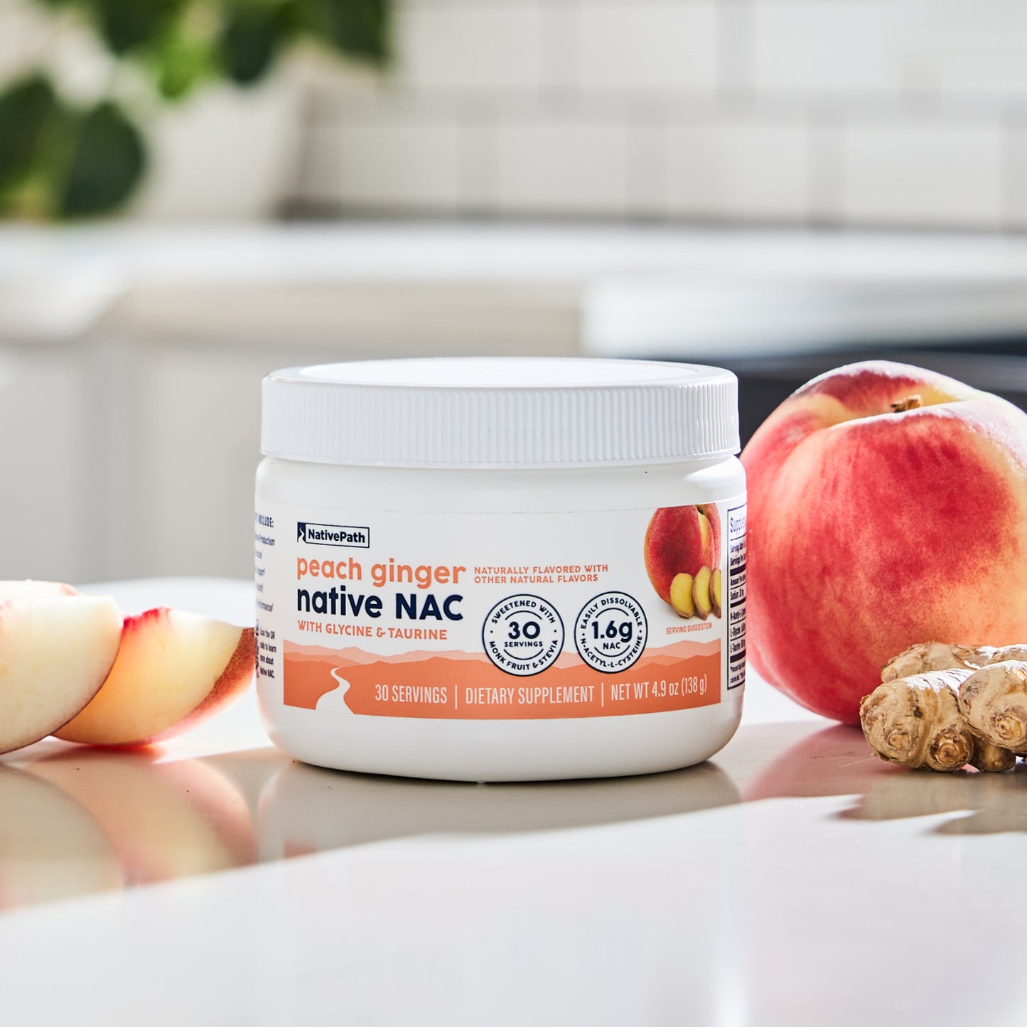 NativePath Peach Ginger Native NAC jar on a kitchen counter beside a fresh peach, peach slices, and ginger root